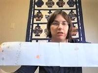 Person holding up a long strip of paper with drawings of the planets on it.