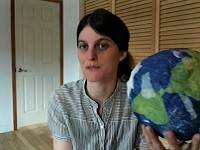 Person holding a paper mache model of the Earth.