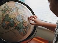 Child touching a globe.