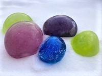 A group of colorful ice orbs, each a different color, outside in snow.