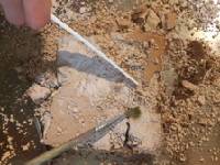 Hand using a small paintbrush to excavate a toy from hardened oobleck.