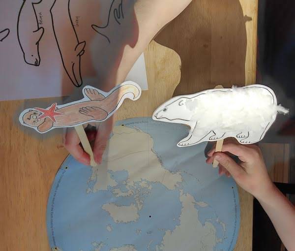 Child's hands playing with sea otter and whale puppets.