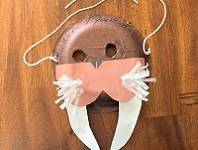 Walrus mask made from a paper plate, construction paper, tissue paper, and yarn.