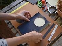 Pair of hands gluing a piece of black construction paper.