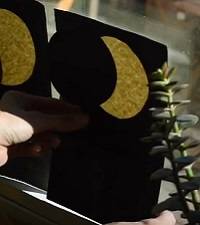 Hand holding a circular shadow puppet in front of a yellow circle representing the Moon.