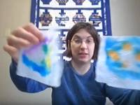 Person holding two paper towels decorated with colorful marker designs.