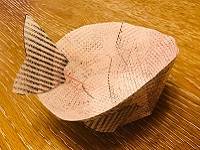 Model fish skin basket, made with paper, with paper fins attached to the sides and back.