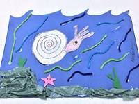 Drawing of an ammonite in an ocean habitat, made up of tissue paper, foam pieces, and yarm.