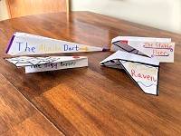 Four paper airplanes in different styles, sitting on a table.