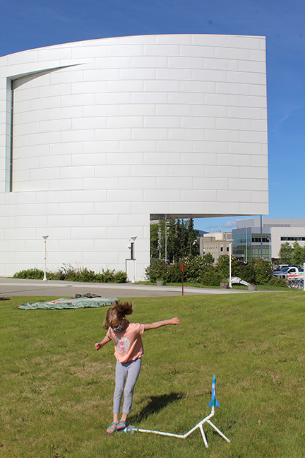 A child jumps onto a stomp rocket launcher in front of the museum.