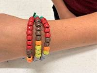 Close-up of a person's wrist wearing a bracelet made of colored beads threaded on a pipecleaner.