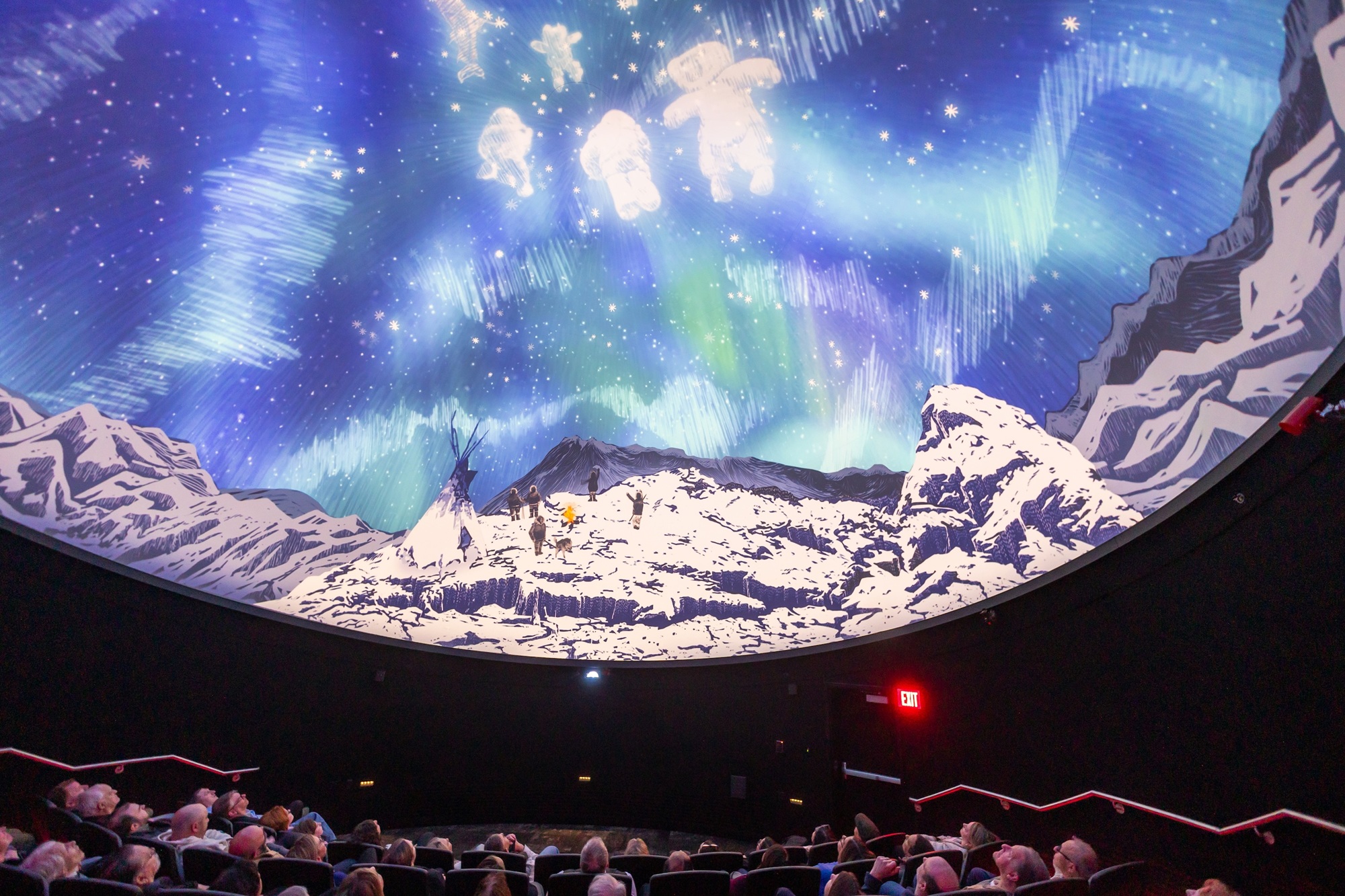 Audience inside planetarium looking at images on dome