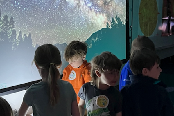 Children in front of a projection of a starry sky
