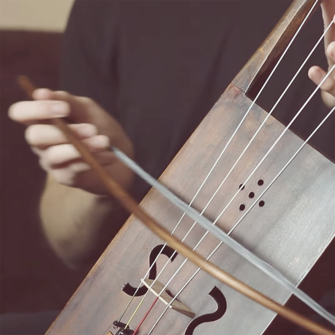 A close up of a musician's hands playing a tagelharpa | Screenshot from YouTube