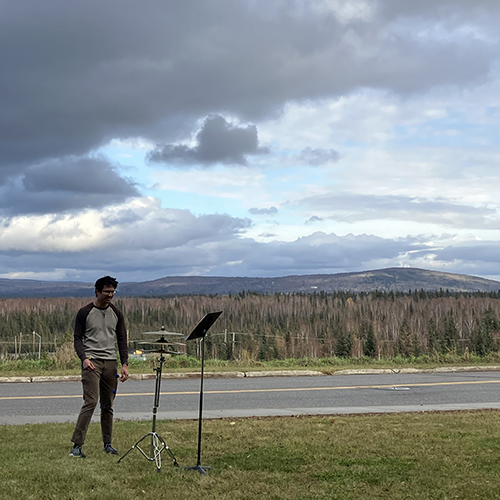 Music major Adrian Ducat performing Inuksuit in rehearsal outside of the music department. Photo courtesy of Sean Dowgray