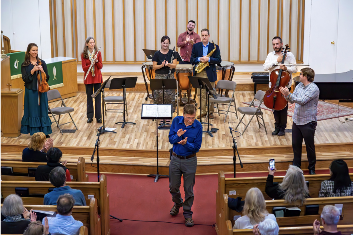 Craig Coray claps his in front of the stage of musicians. UAF Photo
