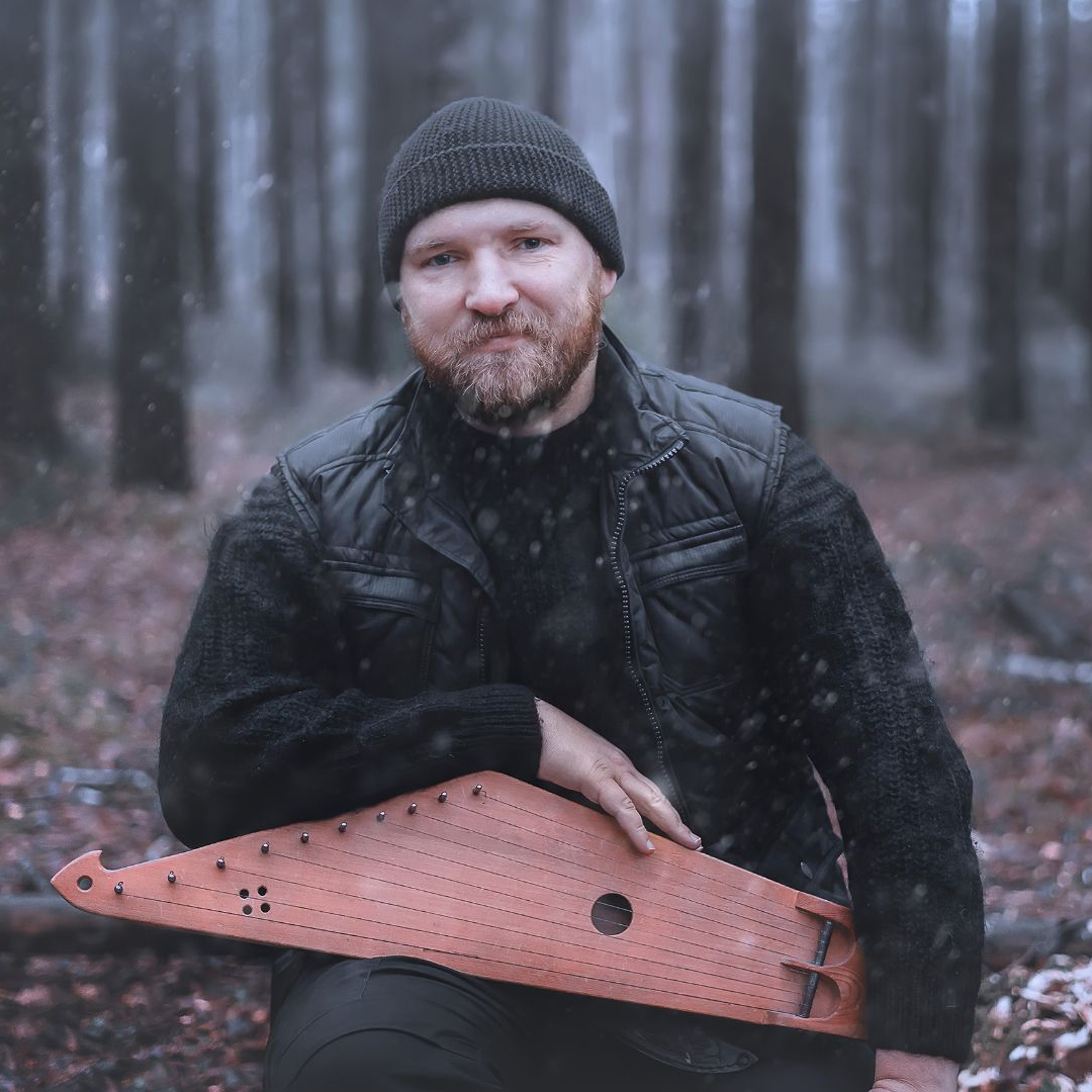 Man in the woods in the winter posing with a kantele | Canva photo