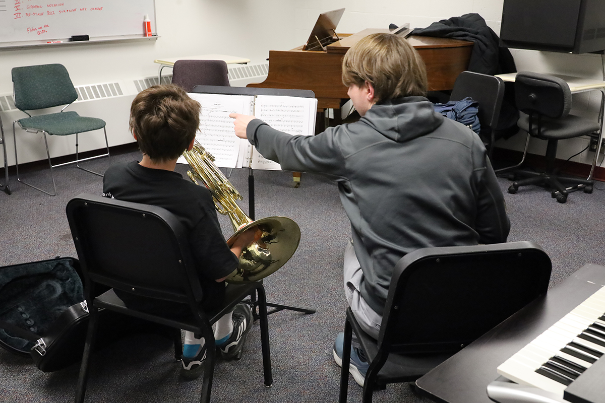 One student points out something on sheet music to another student holding a French horn. UAF Photo by Jaunelle Celaire