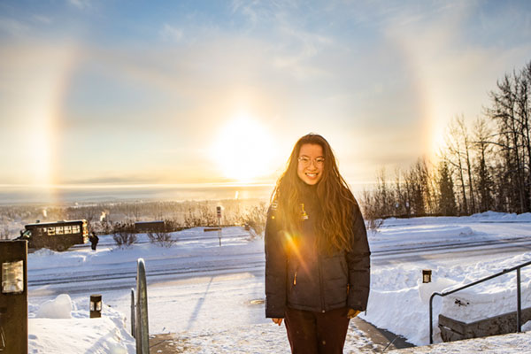 Grace Bifelt stands outside the Patty Center with the winter sunset in the background
