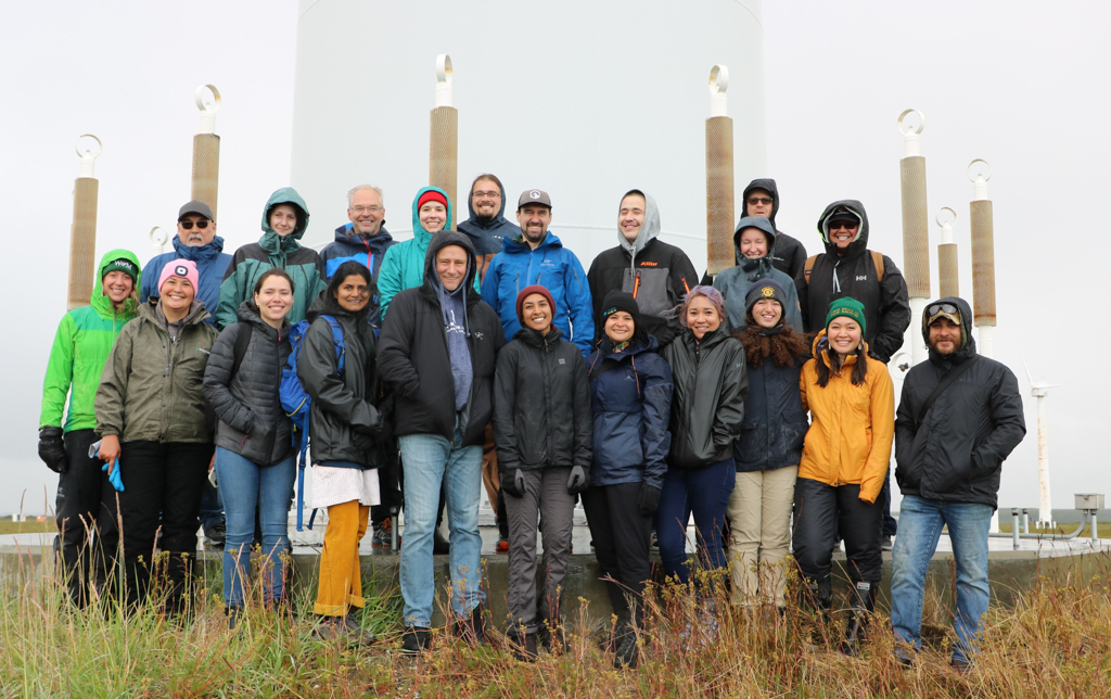 Group of people standing at the base of a wind turbine