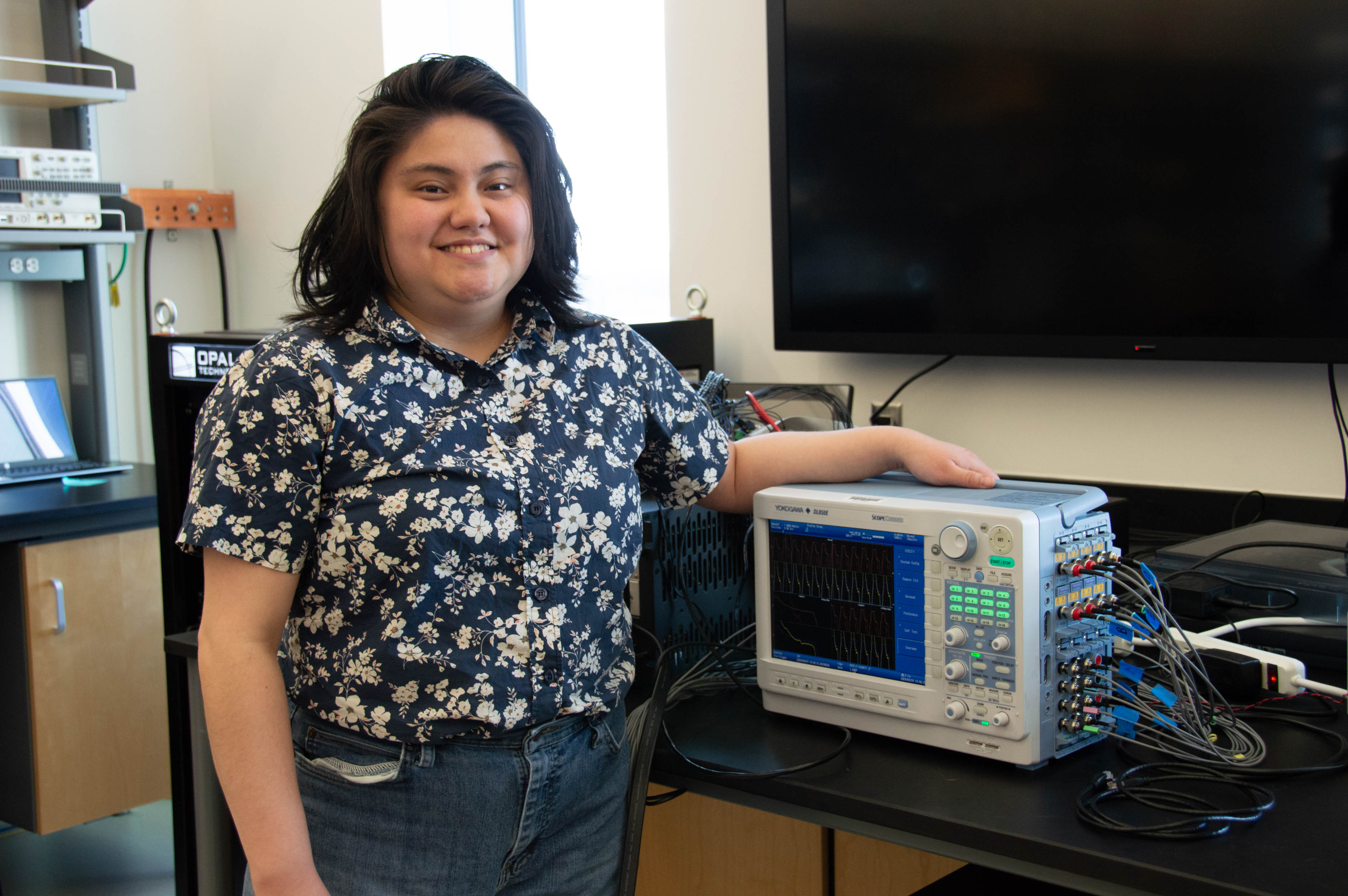 Woman stands beside electronic equipment