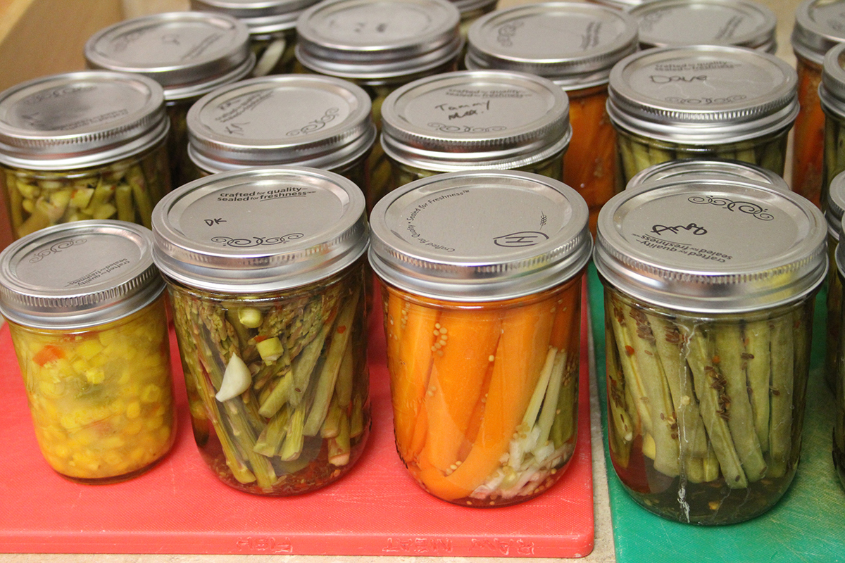 Jars of home-canned vegetables including corn, beans and asparagus.