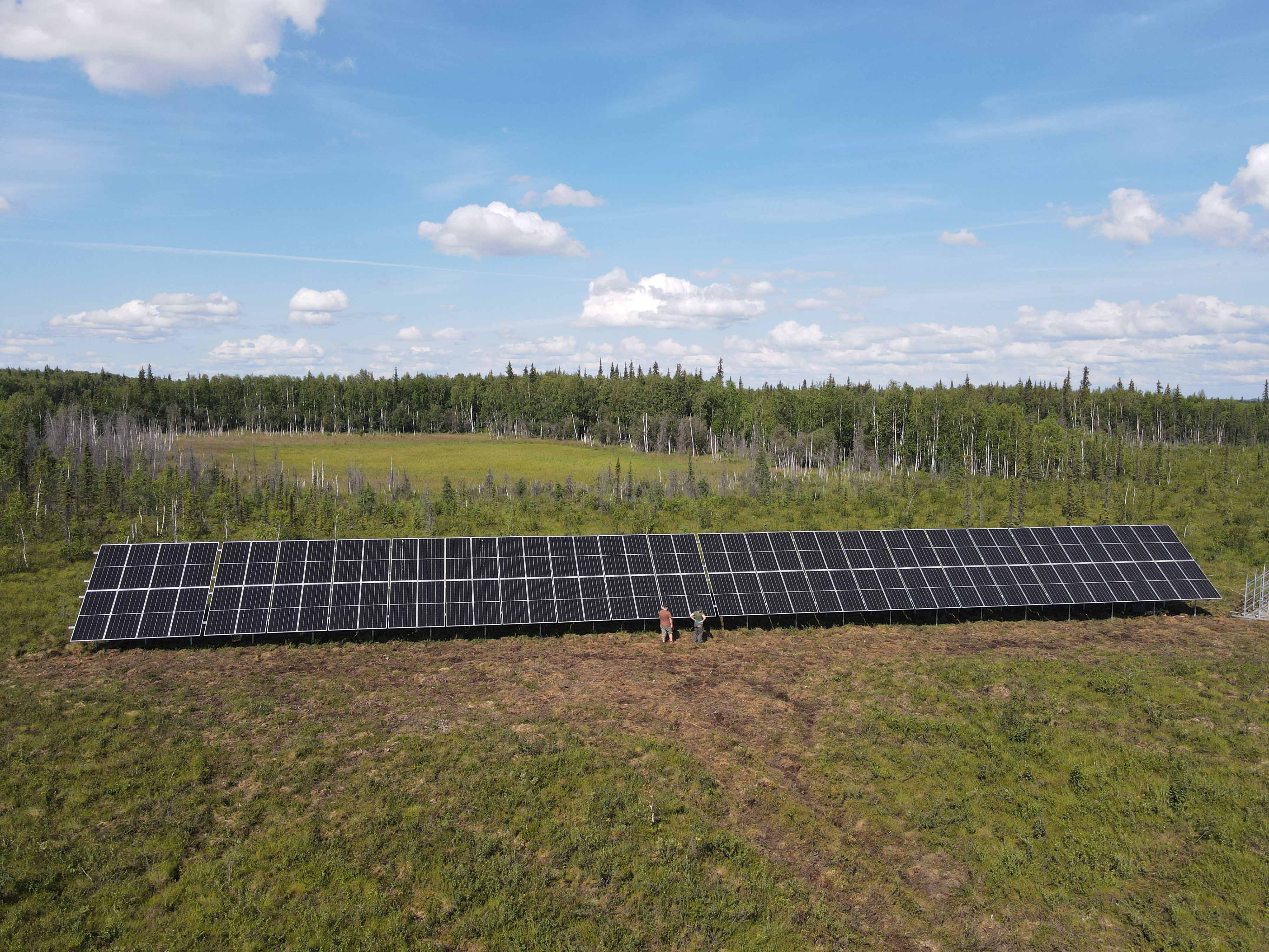 Aerial image if two people walk in front of a large solar array