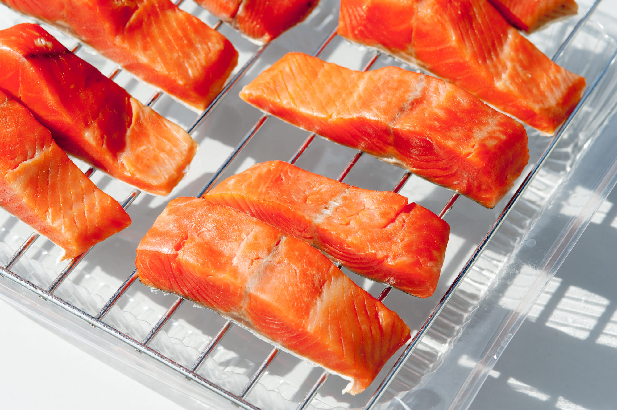 Strips of salmon are laid out on a wire rack prior to being smoked.