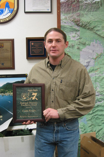 Curtis Knight is writing something down with the core and the coring tool sticking out of the tree.