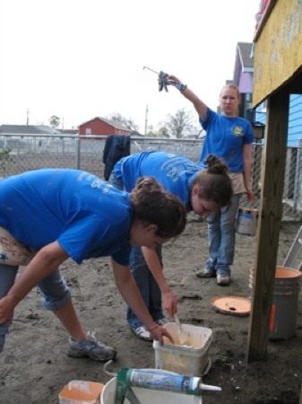 Cynthia Lashinski points out something for Erica and Emily Schooley while they are putting the finishing touches on a Habitat for Humanity house. Photo by Brian Lyke