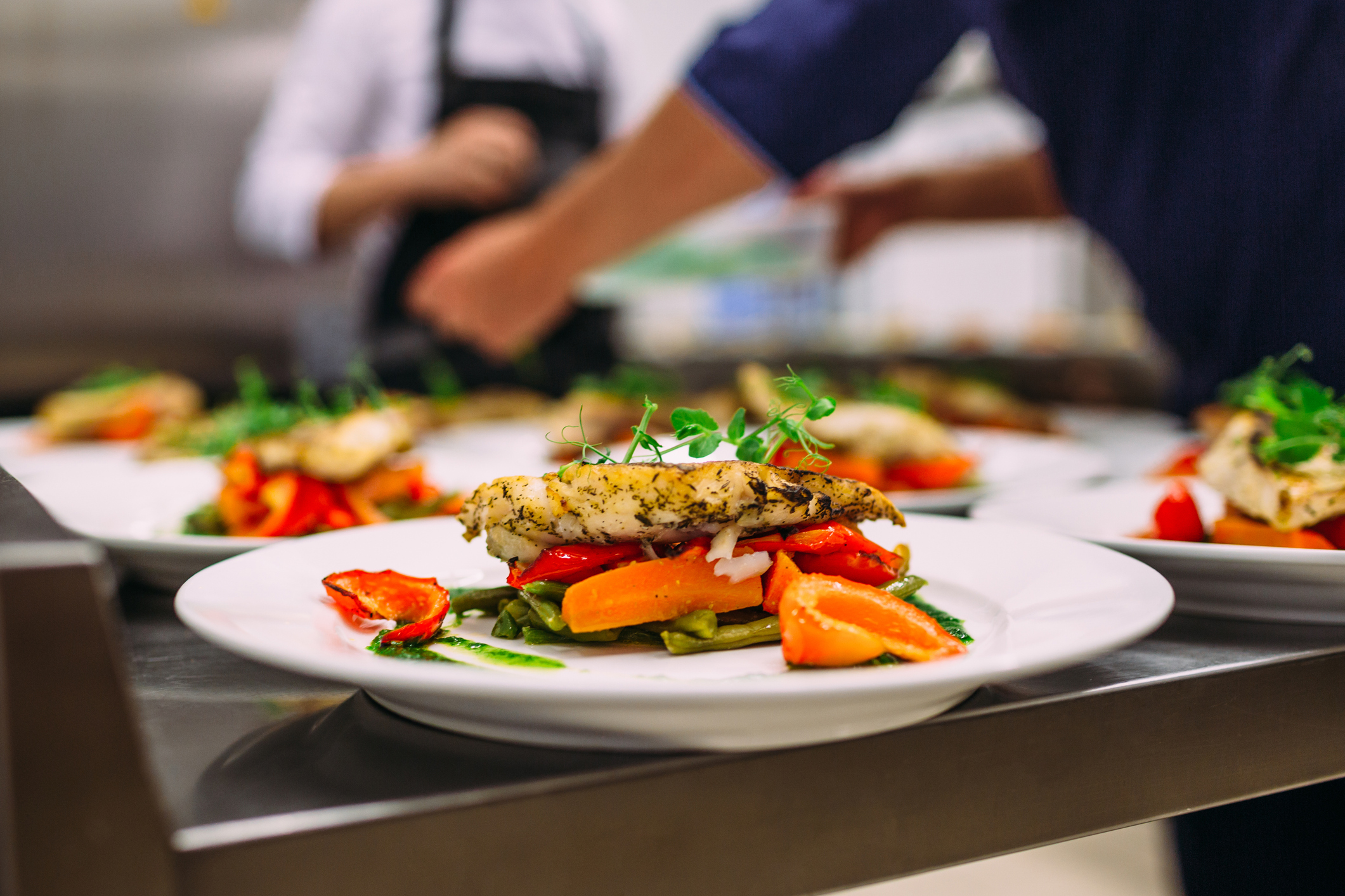A chef prepares plates of meat and vegetables