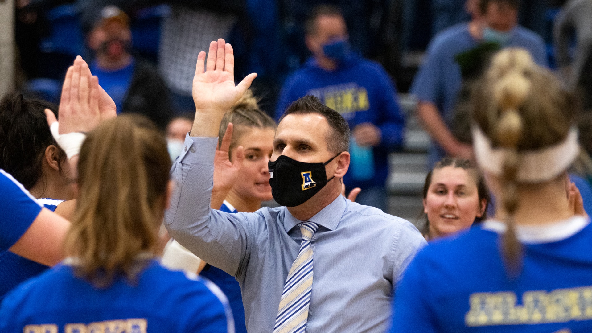 Coach Brian Scott high fives players following a win against Alaska Anchorage.