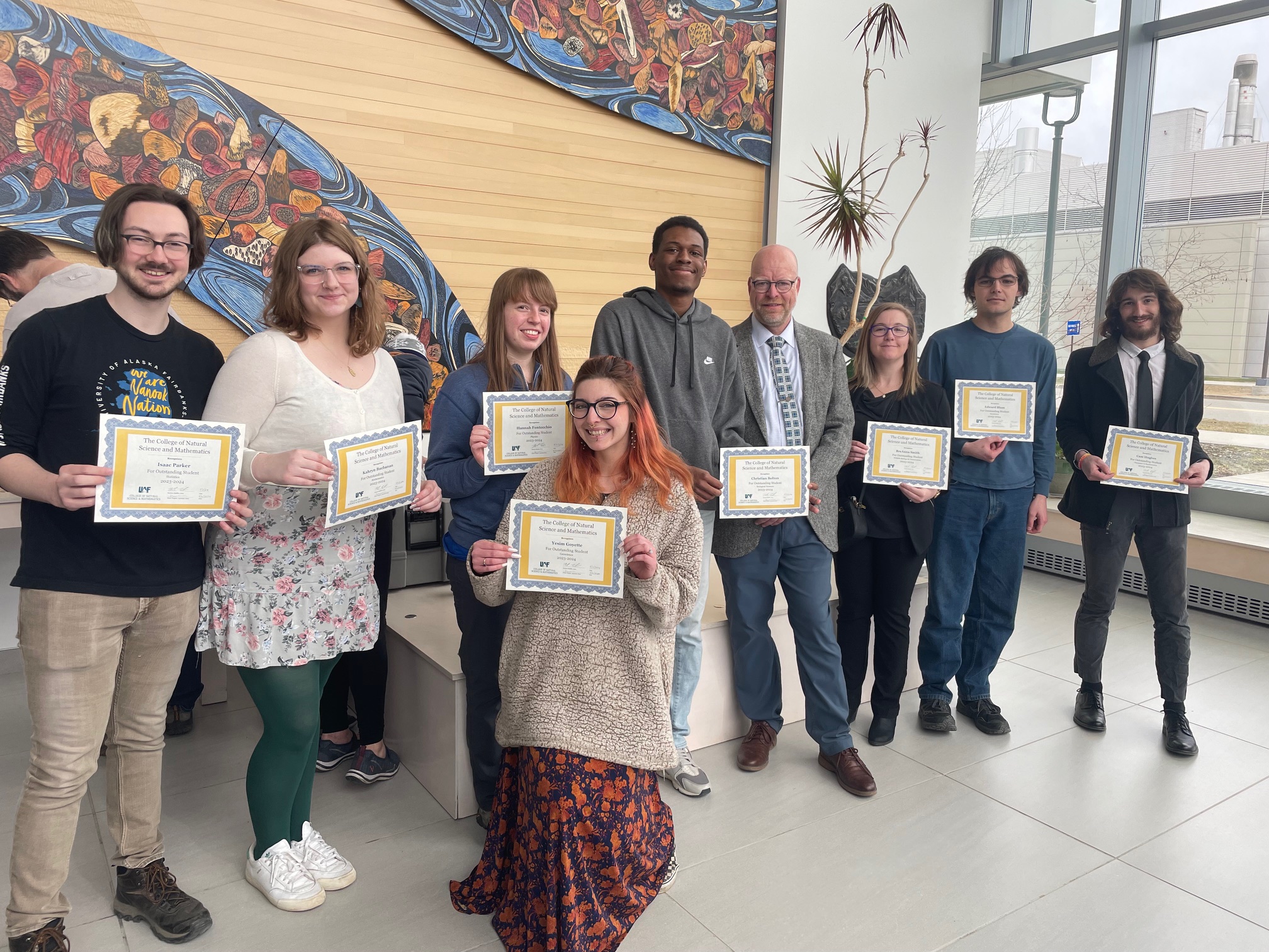 nine people posed holding certificates