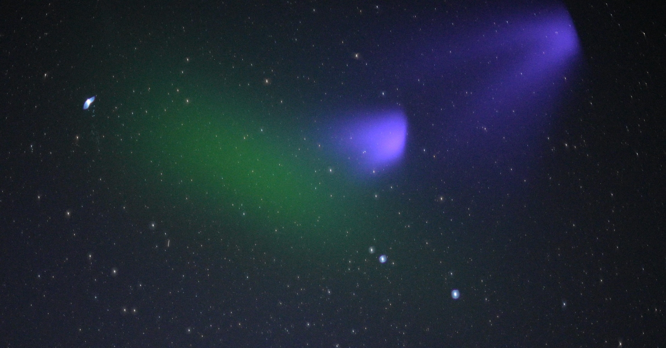 Green and purple hues color an image of the night sky with stars.