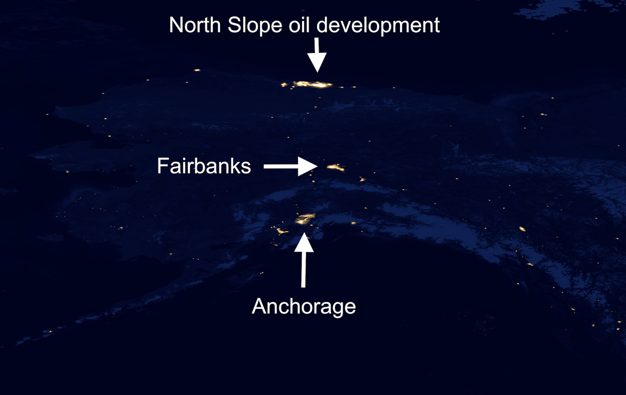 A dark blue satellite image of Alaska shows bright yellow spots at the locations of cities, towns, villages, and major oil production facilities and mines.