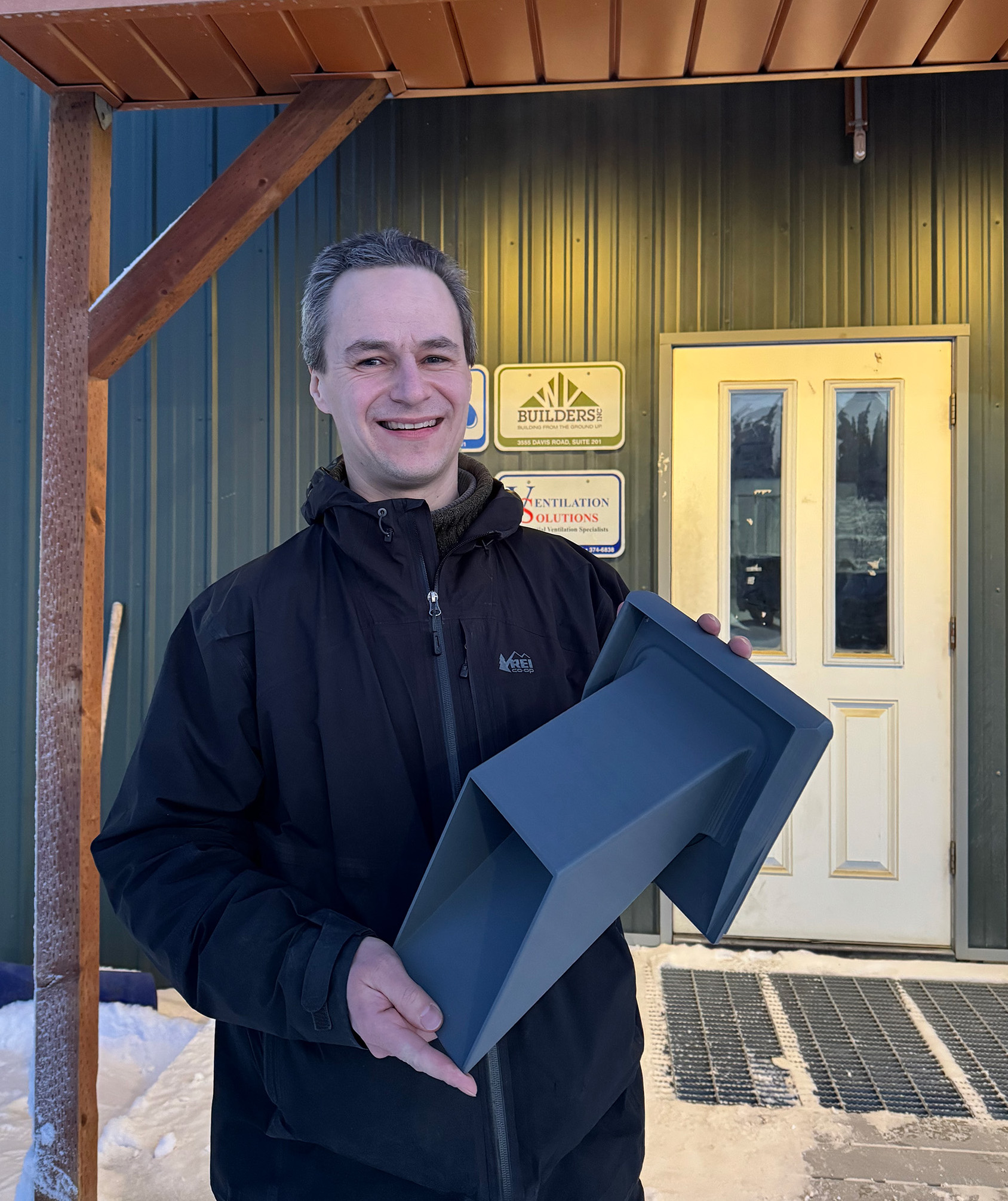 A person holding a ventilation hood in front of a building