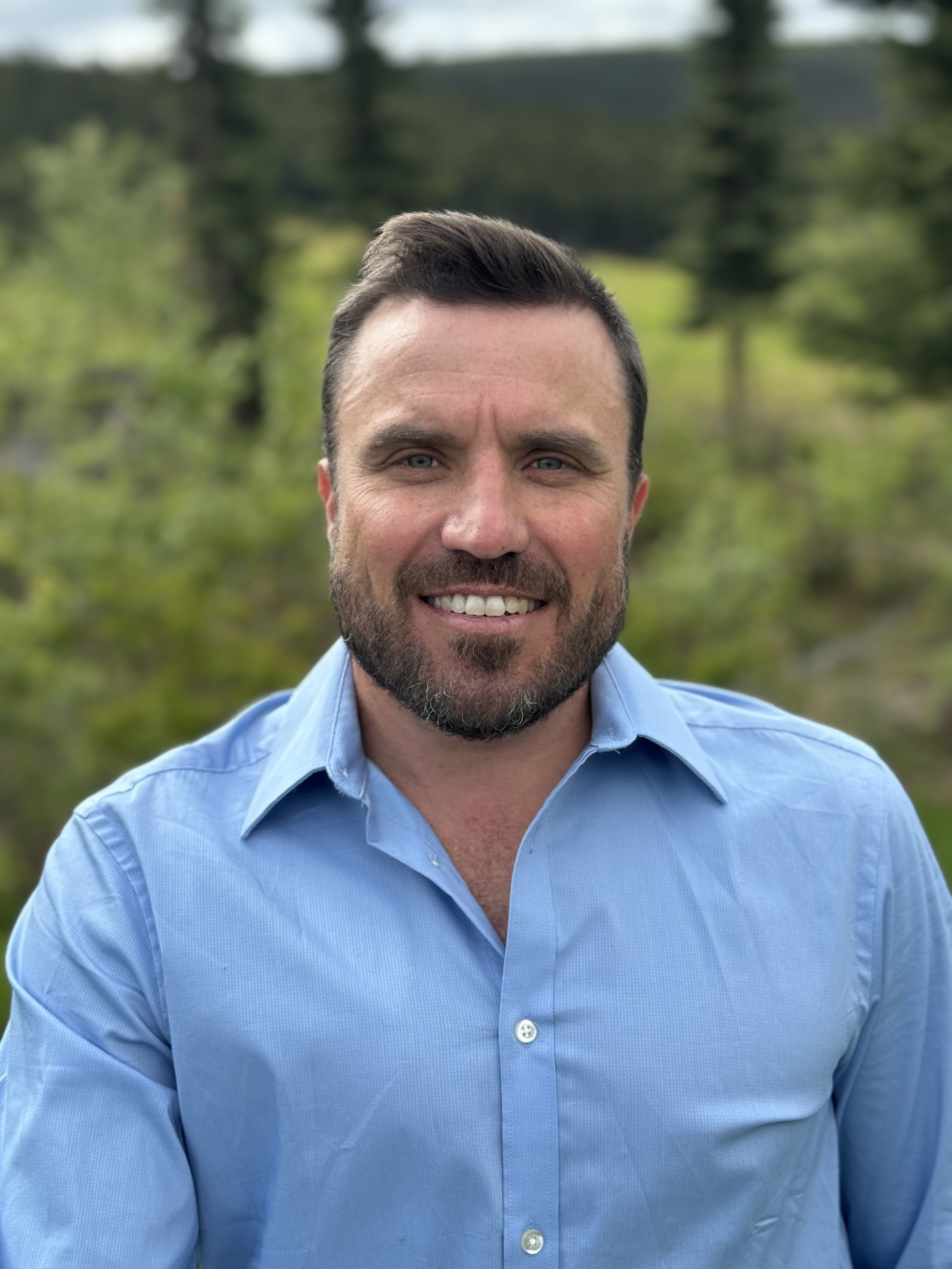 A man wearing a light blue shirt outdoors.
