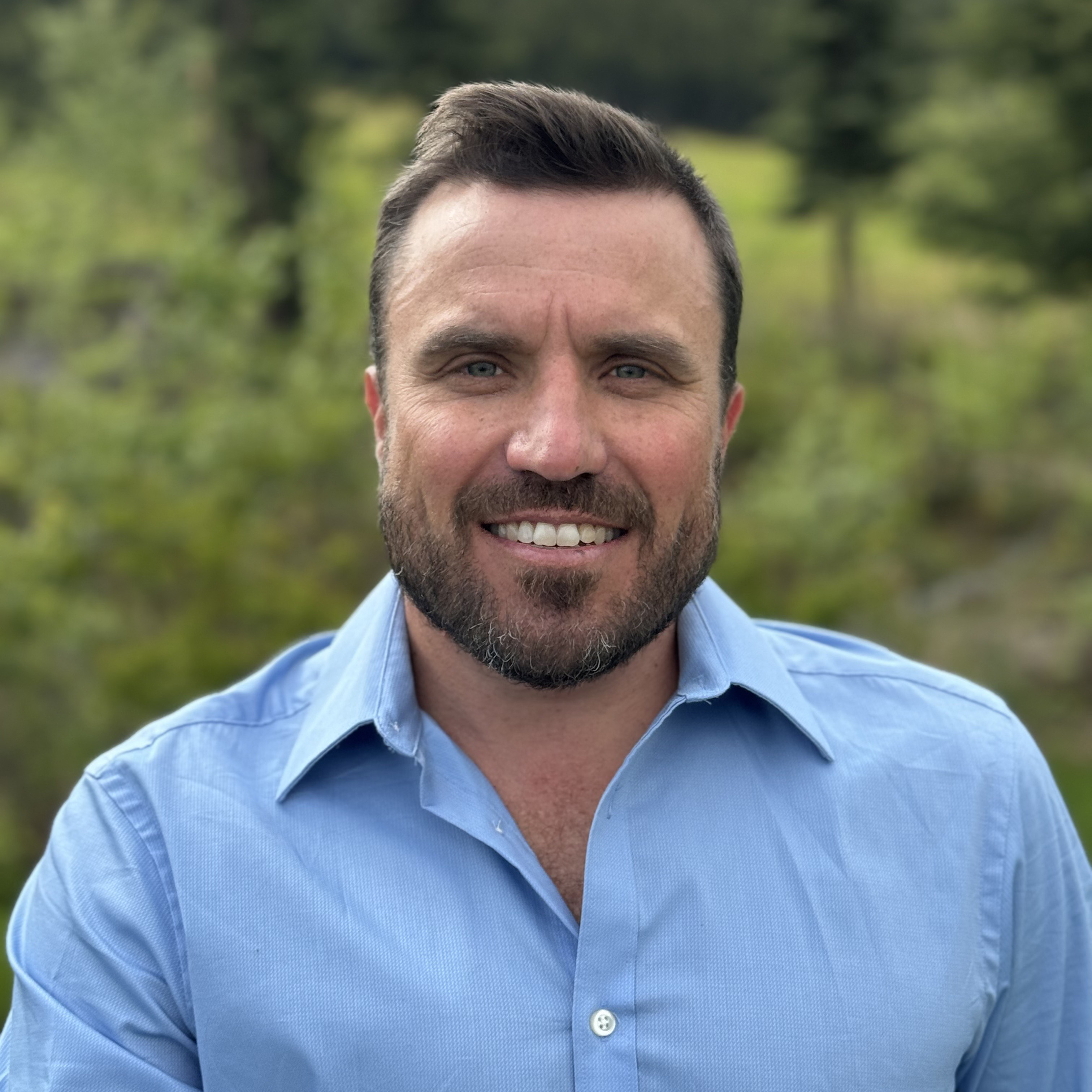 A man wearing a light blue shirt outdoors.