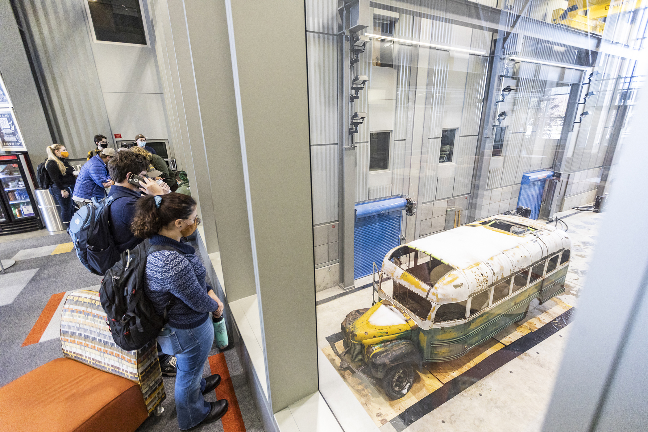 People look at Bus 142 through windows in the engineering building atrium.