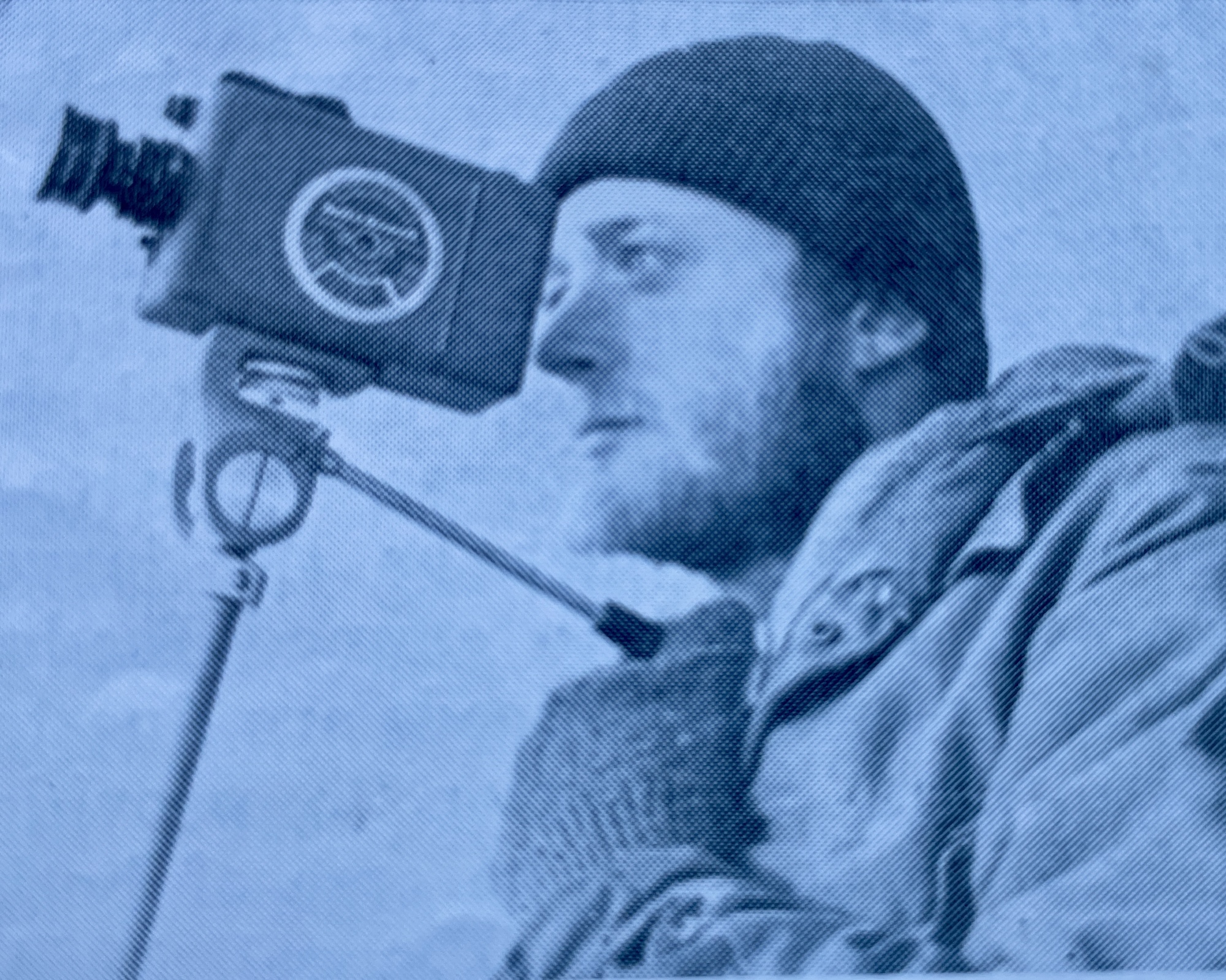 A man wearing mittens and a knit cap looks through an optical instrument.