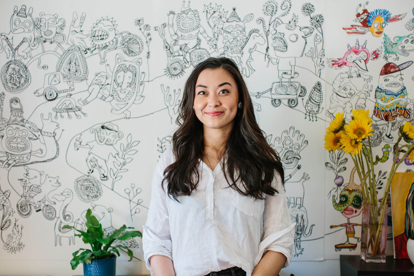 Chanel Miller in front of a wall covered with cartoon illustrations