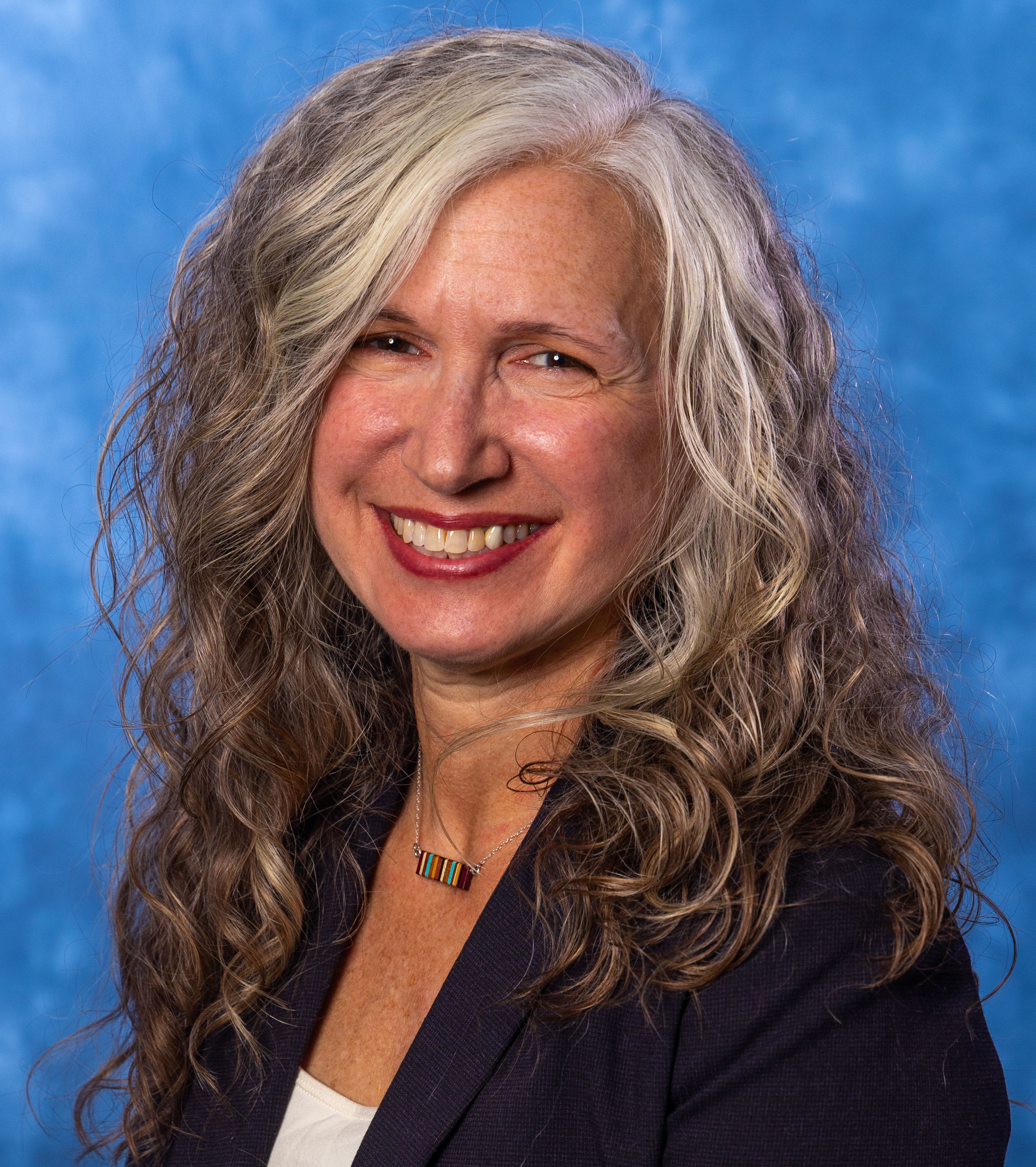 A woman wearing a white shirt and a dark suit jacket.