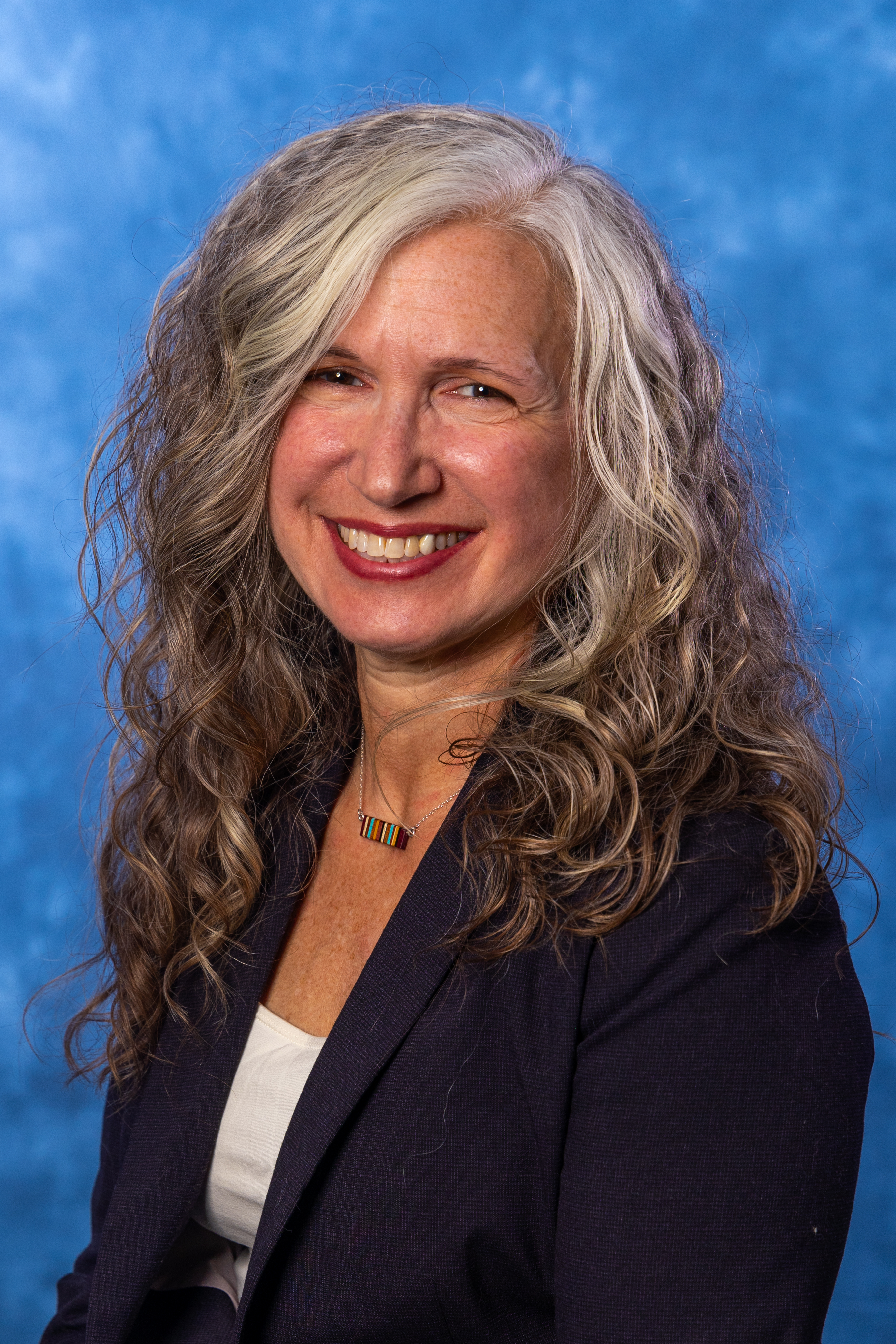A woman wearing a white shirt and a dark suit jacket.