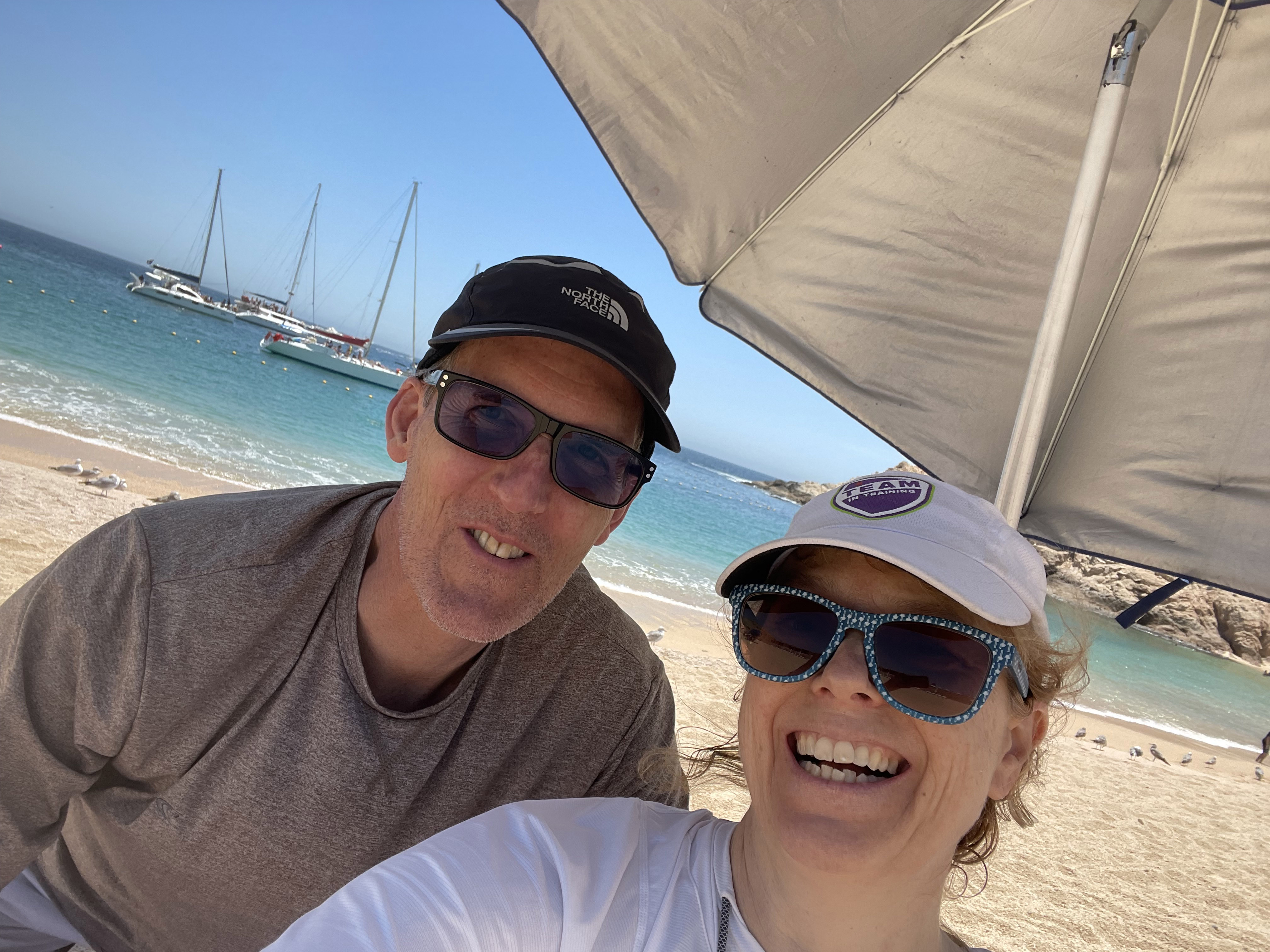 Brendan and Nettie La Belle-Hamer under an umbrella on a beach
