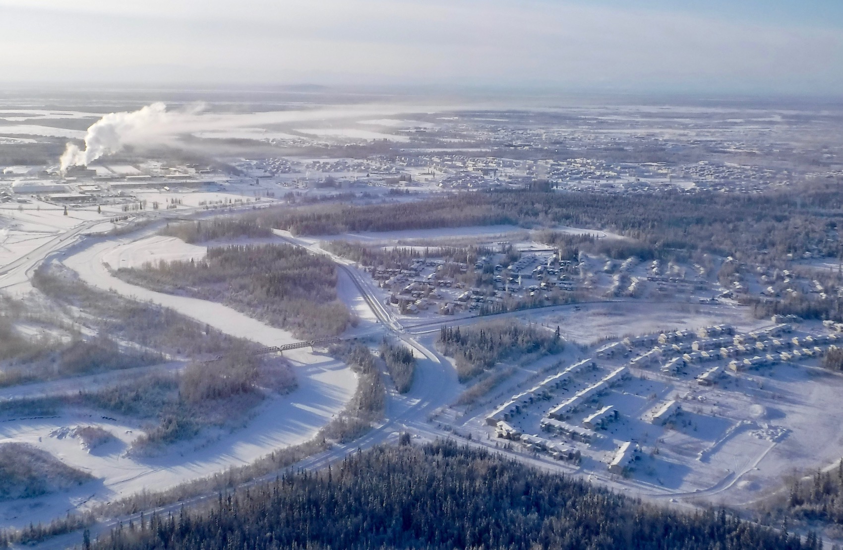 Sunlight touches a snowy city in this aerial view.