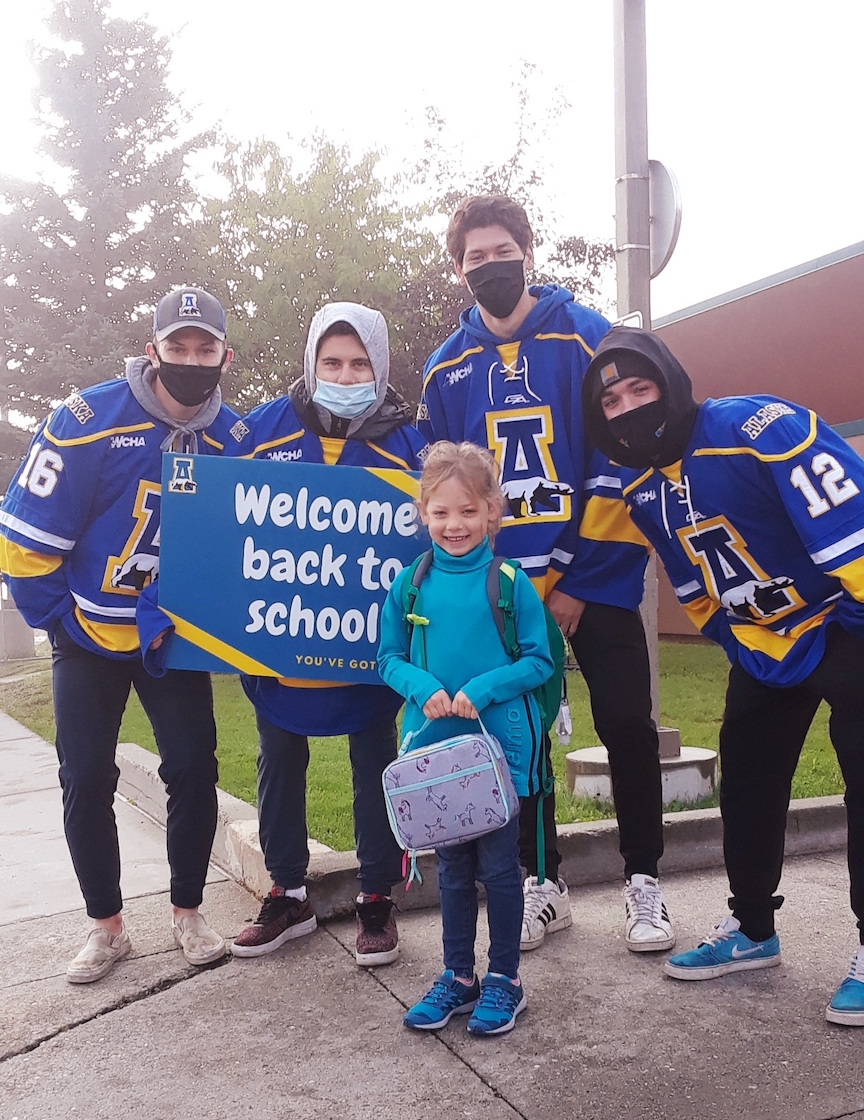 young girl surrounded by UAF athletes