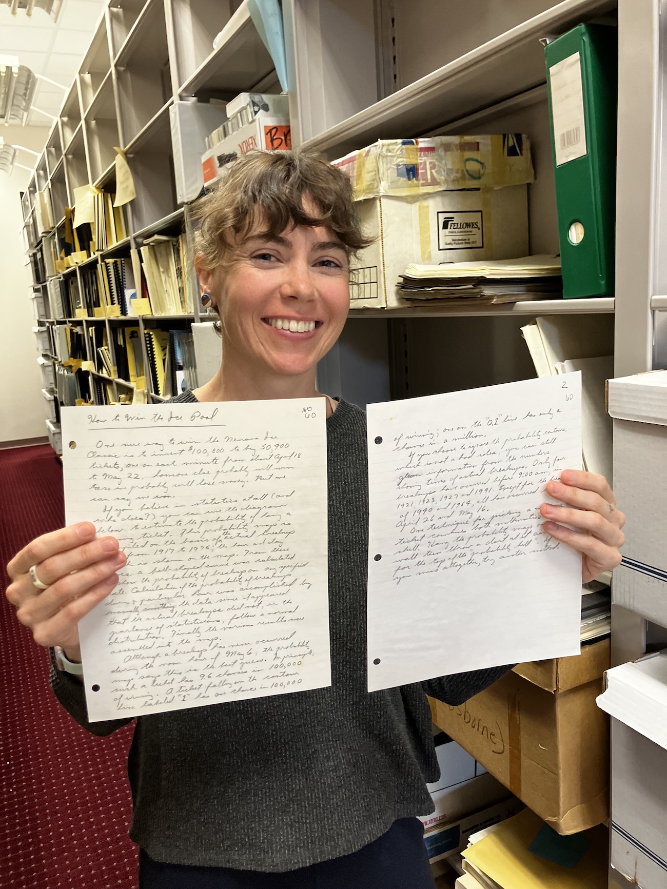 A woman holds two hand-written pages of material.