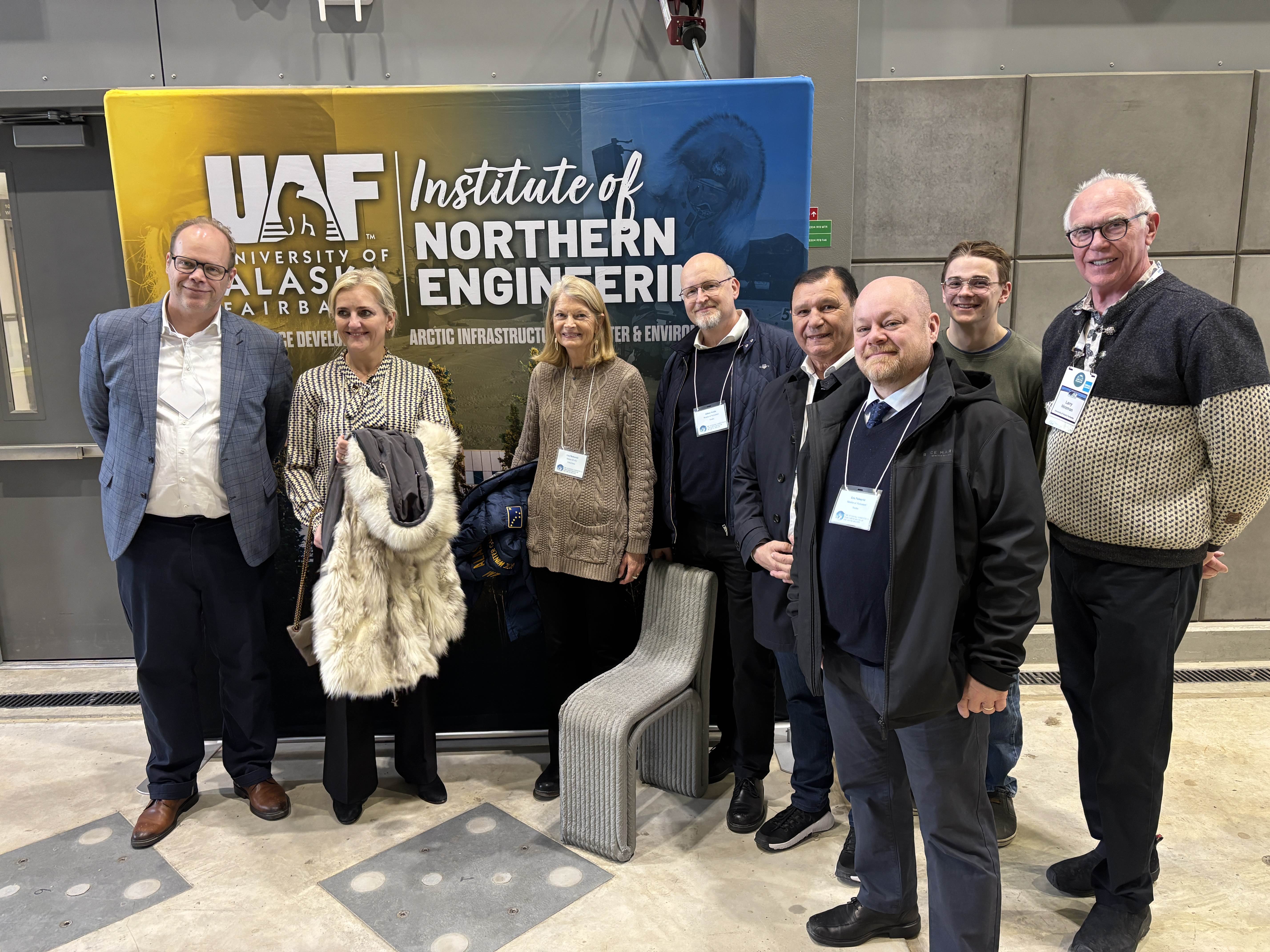 Senator Lisa Murkowski and partners stand in front of a UAF Institute of Northern Engineering sign during their April 18, 2026 visit.