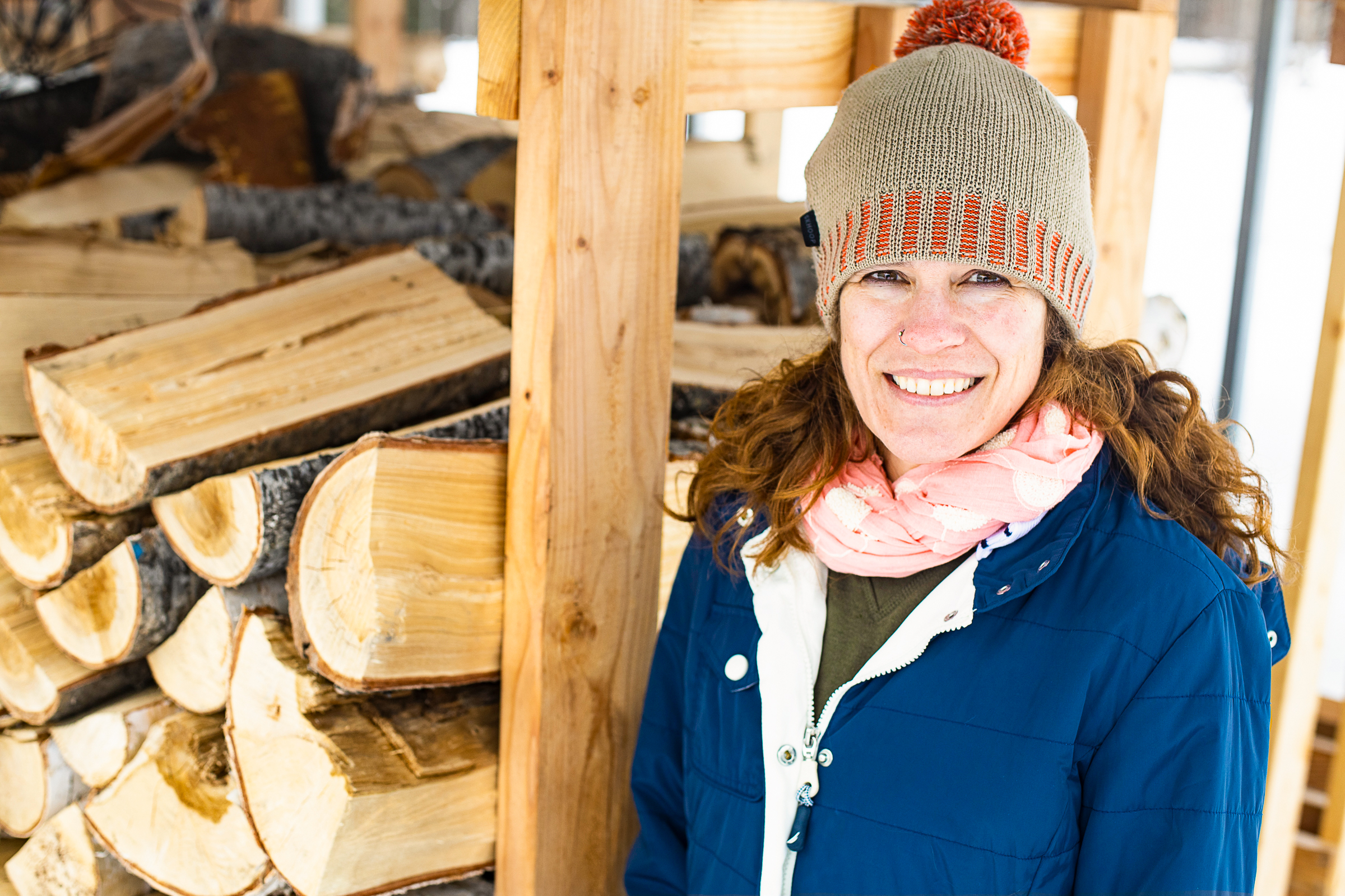 Woman standing next to a stack of firewood