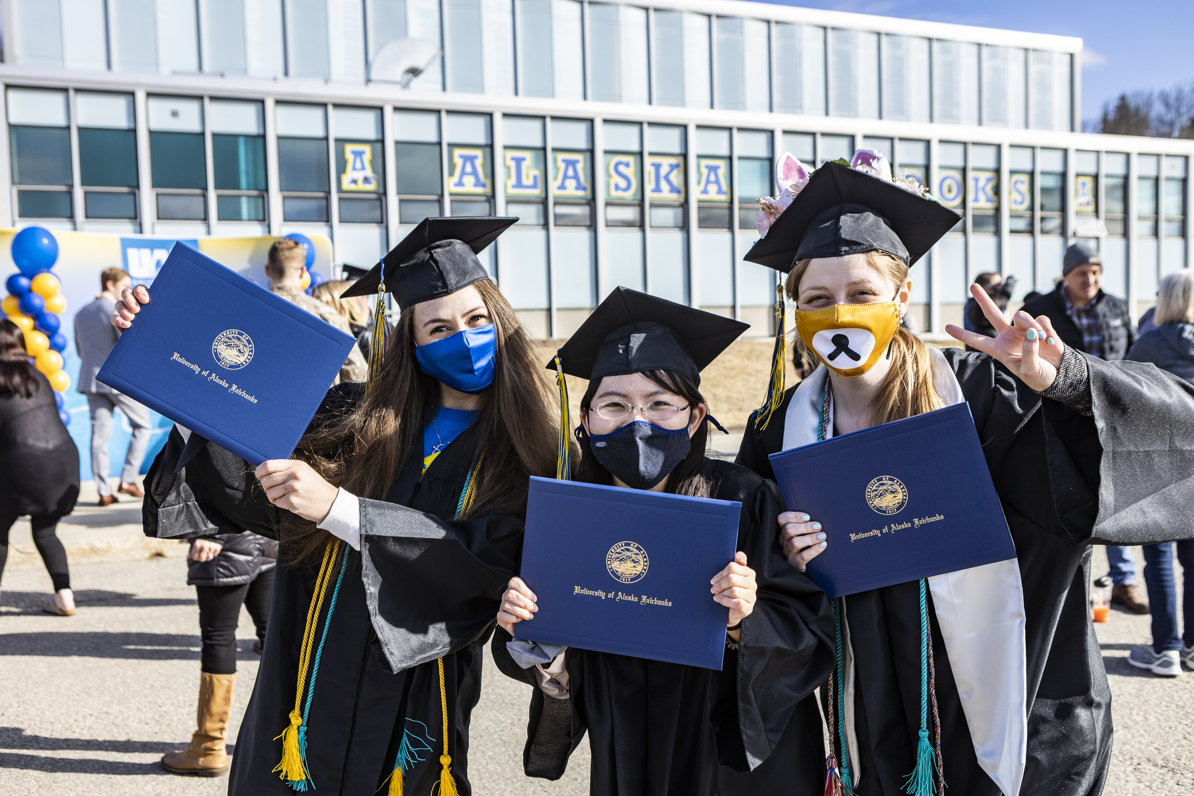Three new UAF graduates display their diplomas